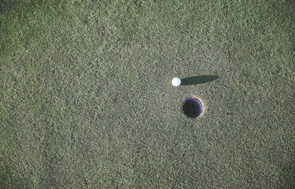 Focus on the target white golf ball near hole