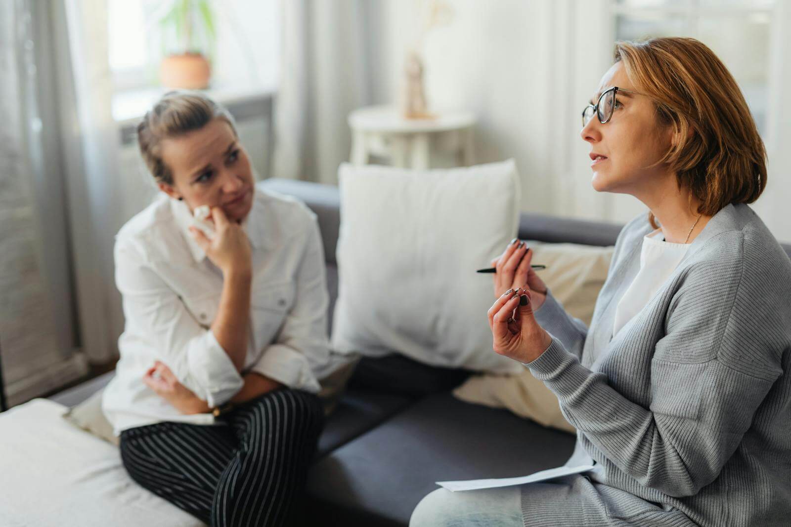 Photo by www.kaboompics.com Two women engaged in a thoughtful counseling session in a cozy indoor setting of whom one is a life coach speaking and the other is the client listening.