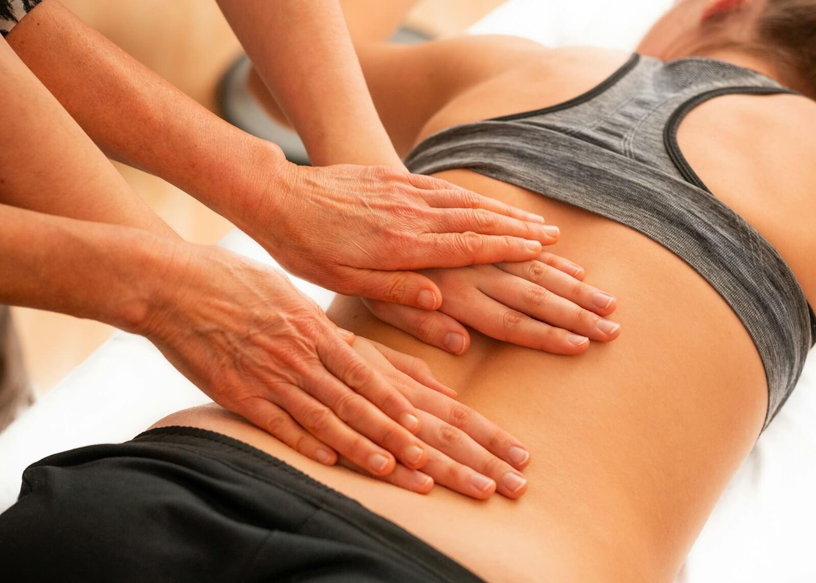 woman in black and white tank top that gets a massage for lower back pain