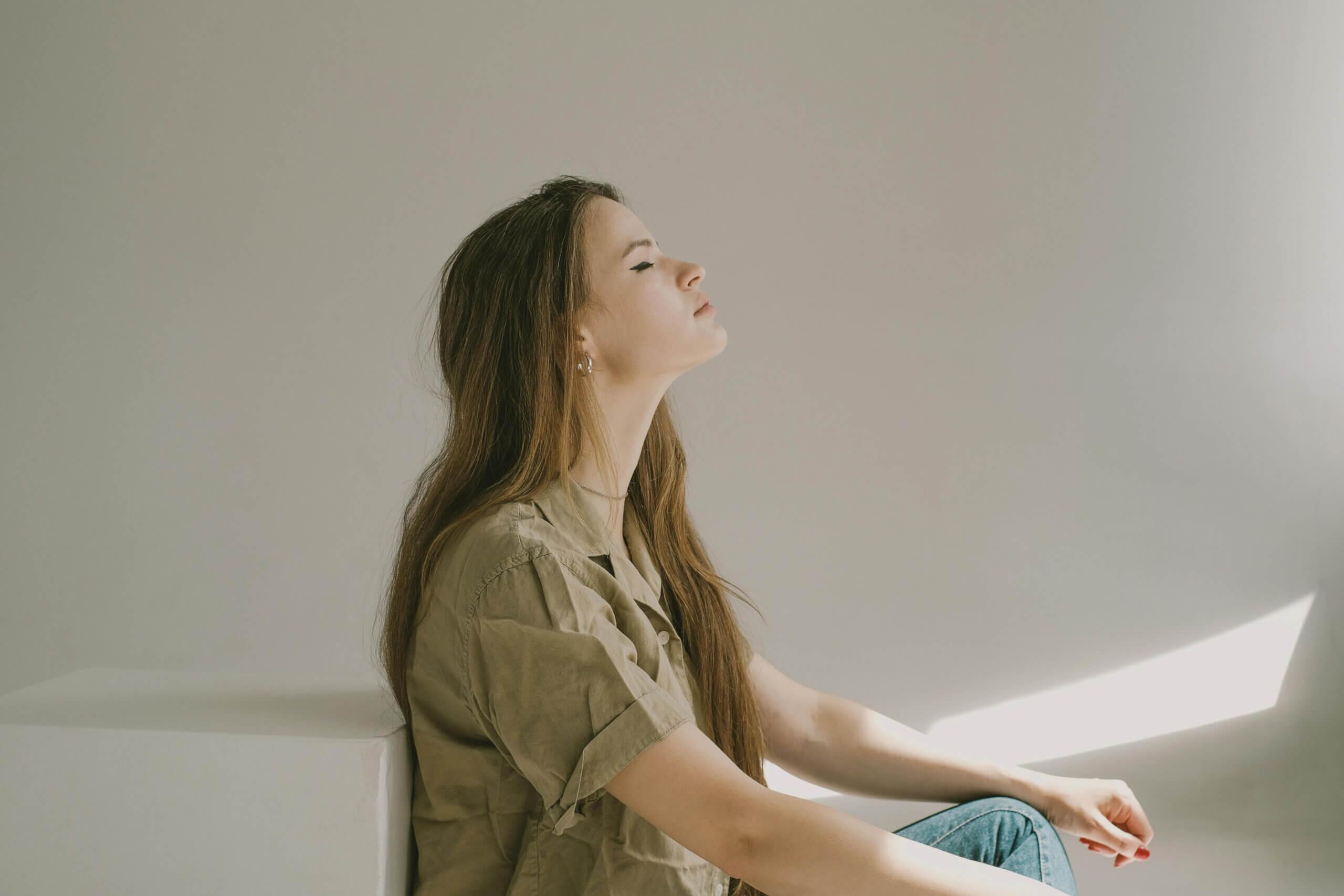 Beautiful girl with long hair and closed eyes sitting on a floor meditating