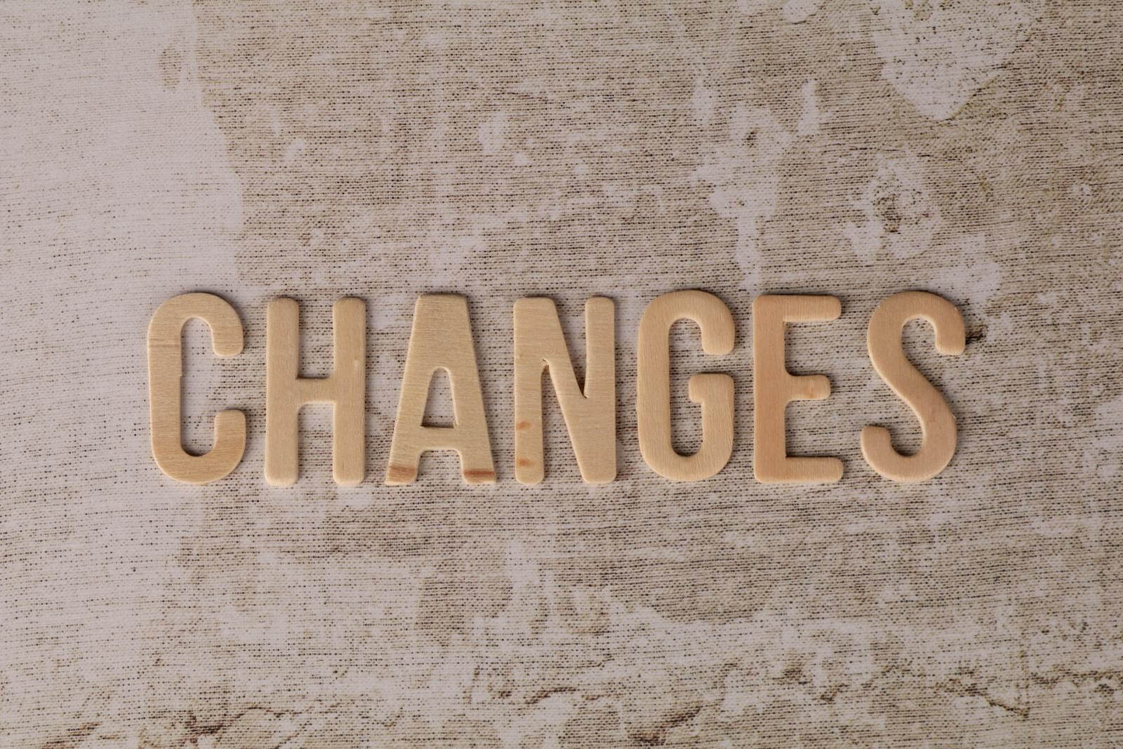 Wooden letters arranged to form 'Changes' on a textured, rustic surface.